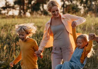 Parents and children smiling while walking outdoors together in a field.